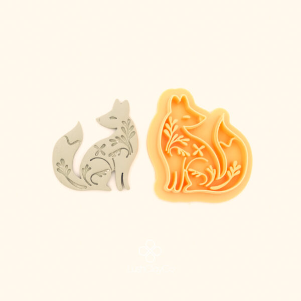 Rävna Fox wildlife polymer clay cutter alongside clay impression showing seated fox silhouette with detailed floral and botanical interior fill