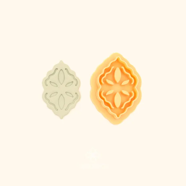 Sırma Nakış ottoman polymer clay cutter alongside clay impression showing rounded oval shield form with four-way floral cross motif and teardrop petals