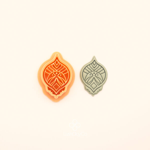 Zerrin hatayi polymer clay cutter alongside clay impression showing pointed oval silhouette with central diamond form, curved leaf detail and dot clusters