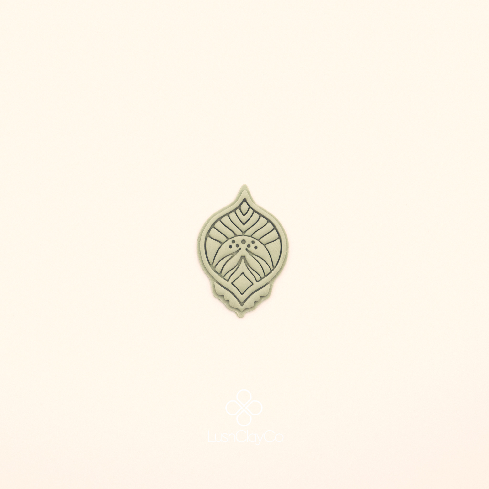 Clay impression of the Zerrin hatayi cutter showing central diamond form flanked by curved leaf forms with fine vein lines and dot clusters pressed into polymer clay